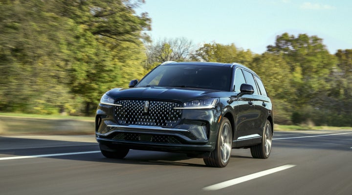 A 2026 Lincoln Black Label™ Aviator® SUV is being driven down a road lined with trees. | Deacon Jones Lincoln in Goldsboro NC