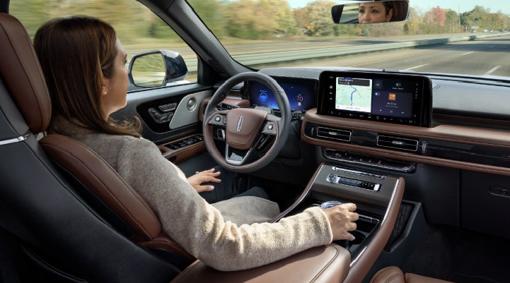 A 2027 Lincoln Aviator® SUV is being driven hands-free on a highway lined with trees. | Deacon Jones Lincoln in Goldsboro NC
