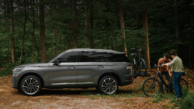 A father and son load e-bikes on a bike rack attached to a 2027 Lincoln Aviator® SUV. | Deacon Jones Lincoln in Goldsboro NC
