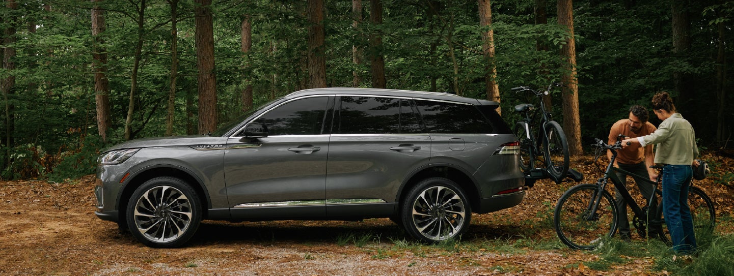 A father and son load e-bikes on a bike rack attached to a 2027 Lincoln Aviator® SUV. | Deacon Jones Lincoln in Goldsboro NC